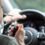 Man driving lighting a cigarette