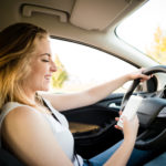 Girl viewing her phone while driving Girl viewing her phone while driving