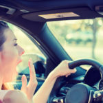 A woman yawning while driving A woman yawning while driving
