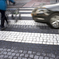 A guy pushing a stroller across the road