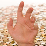 Hand reaching from below layer of coins to depict debt Hand reaching from below layer of coins to depict debt