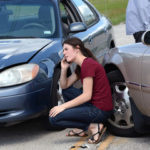 Lady that is on the phone trying to figure out who is liable for damages in a car crash pictured Lady that is on the phone trying to figure out who is liable for damages in a car crash pictured