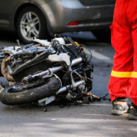 Crashed motorcycle after road accident with a car