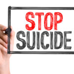 Hand with marker writing the word Stop Suicide Hand with marker writing the word Stop Suicide