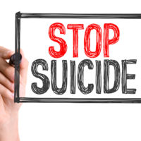 Hand with marker writing the word Stop Suicide