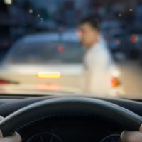 A pedestrian crossing the street in front of driver in car