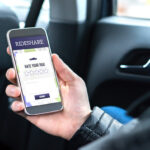 Ride share customer and passenger sitting in the backseat of a car while using the rideshare application in smartphone to give rating to the driver. Commuter and rider giving review in phone taxi app. Ride share customer and passenger sitting in the backseat of a car while using the rideshare application in smartphone to give rating to the driver. Commuter and rider giving review in phone taxi app.