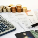 close up of a credit cards with credit card statements, pen, stack of coins and calculator on white background, financial concept, selective focus close up of a credit cards with credit card statements, pen, stack of coins and calculator on white background, financial concept, selective focus