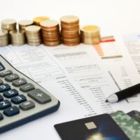 close up of a credit cards with credit card statements, pen, stack of coins and calculator on white background, financial concept, selective focus