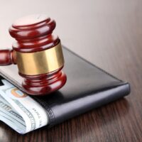 Gavel and money in wallet on wooden background