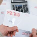 Close-up Of Businessperson Hand Holding Past Due Envelope Close-up Of Businessperson Hand Holding Past Due Envelope