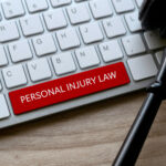Selective focus of gavel and computer keyboard with red key written with Personal Injury Law on a wooden background.