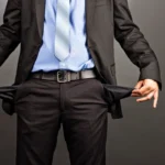 Businessman in suit pulling empty pockets, symbolizing financial hardship